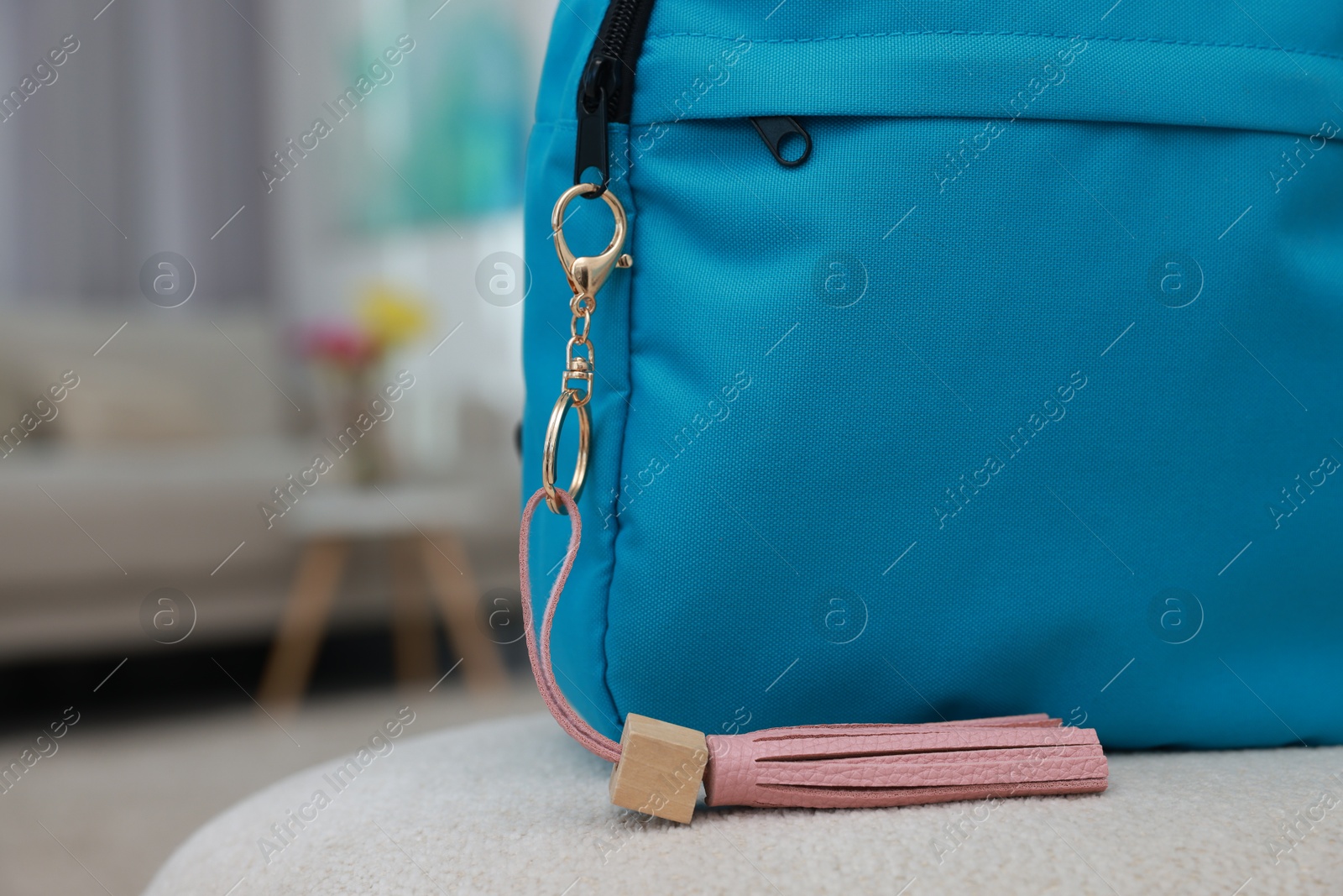 Photo of Backpack with pink leather keychain on soft surface indoors, closeup