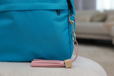 Photo of Backpack with pink leather keychain on soft surface indoors, closeup