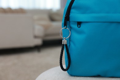 Photo of Backpack with black leather keychain on soft surface indoors, closeup. Space for text