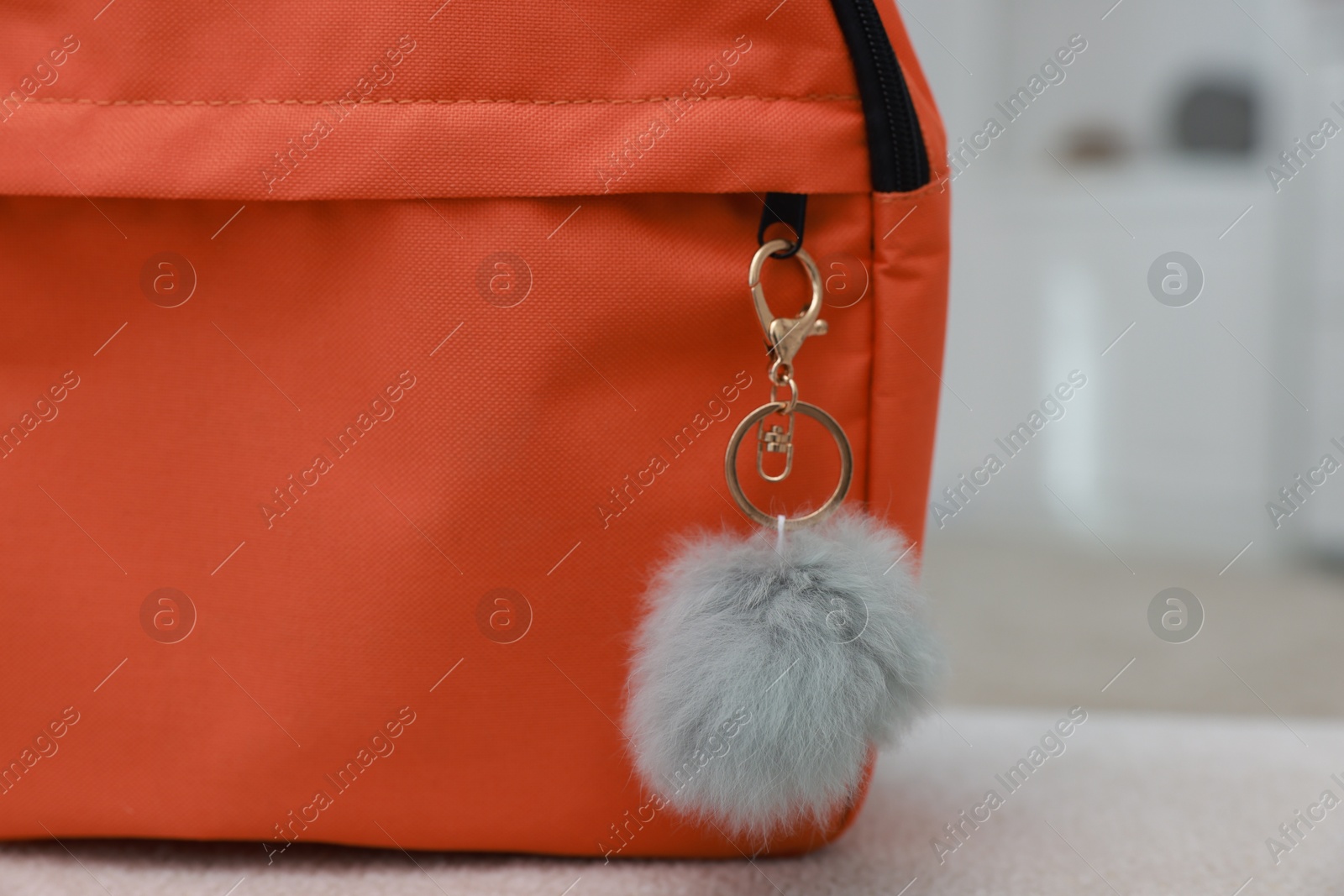 Photo of Backpack with faux fur keychain on soft surface indoors, closeup