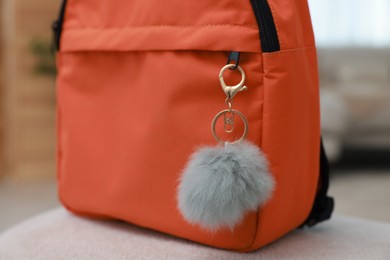 Photo of Backpack with faux fur keychain on soft surface indoors, closeup