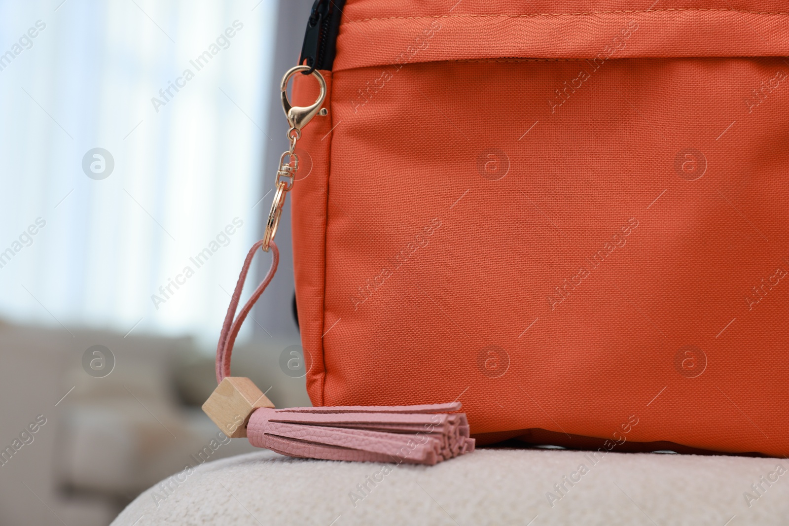 Photo of Backpack with pink leather keychain on soft surface indoors, closeup