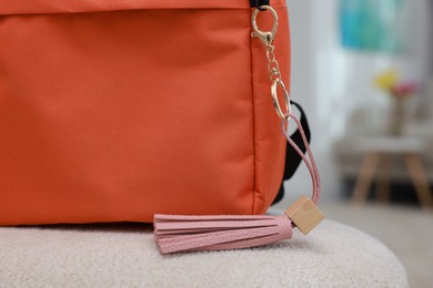 Photo of Backpack with pink leather keychain on soft surface indoors, closeup