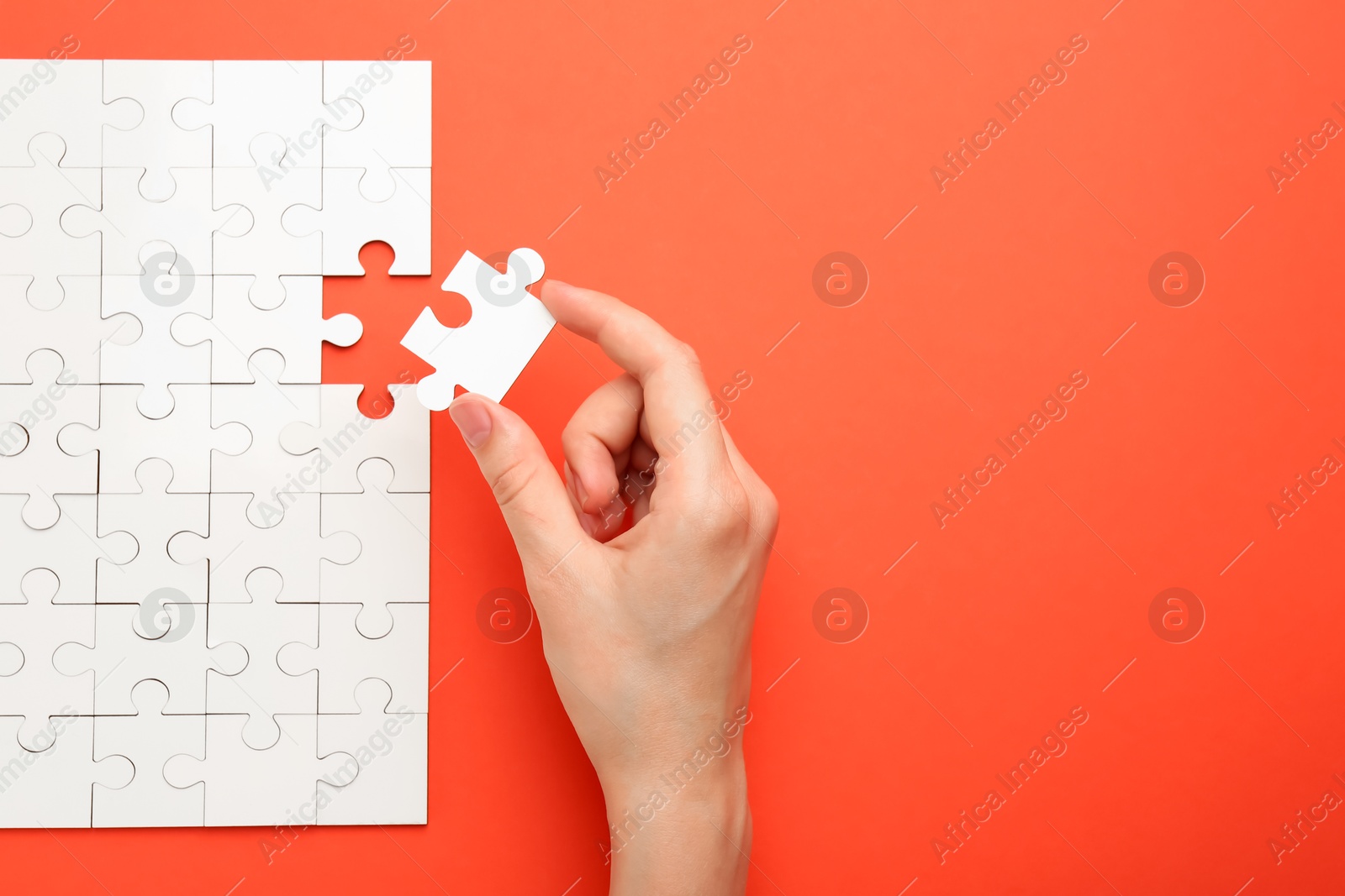 Photo of Woman solving white puzzle on red background, closeup. Space for text