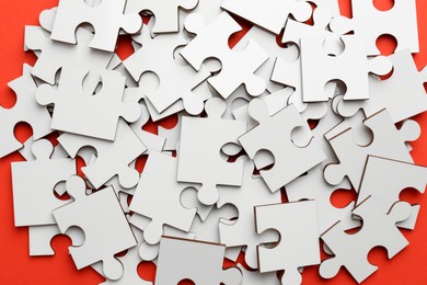 Photo of Pile of white puzzle pieces on red background, closeup