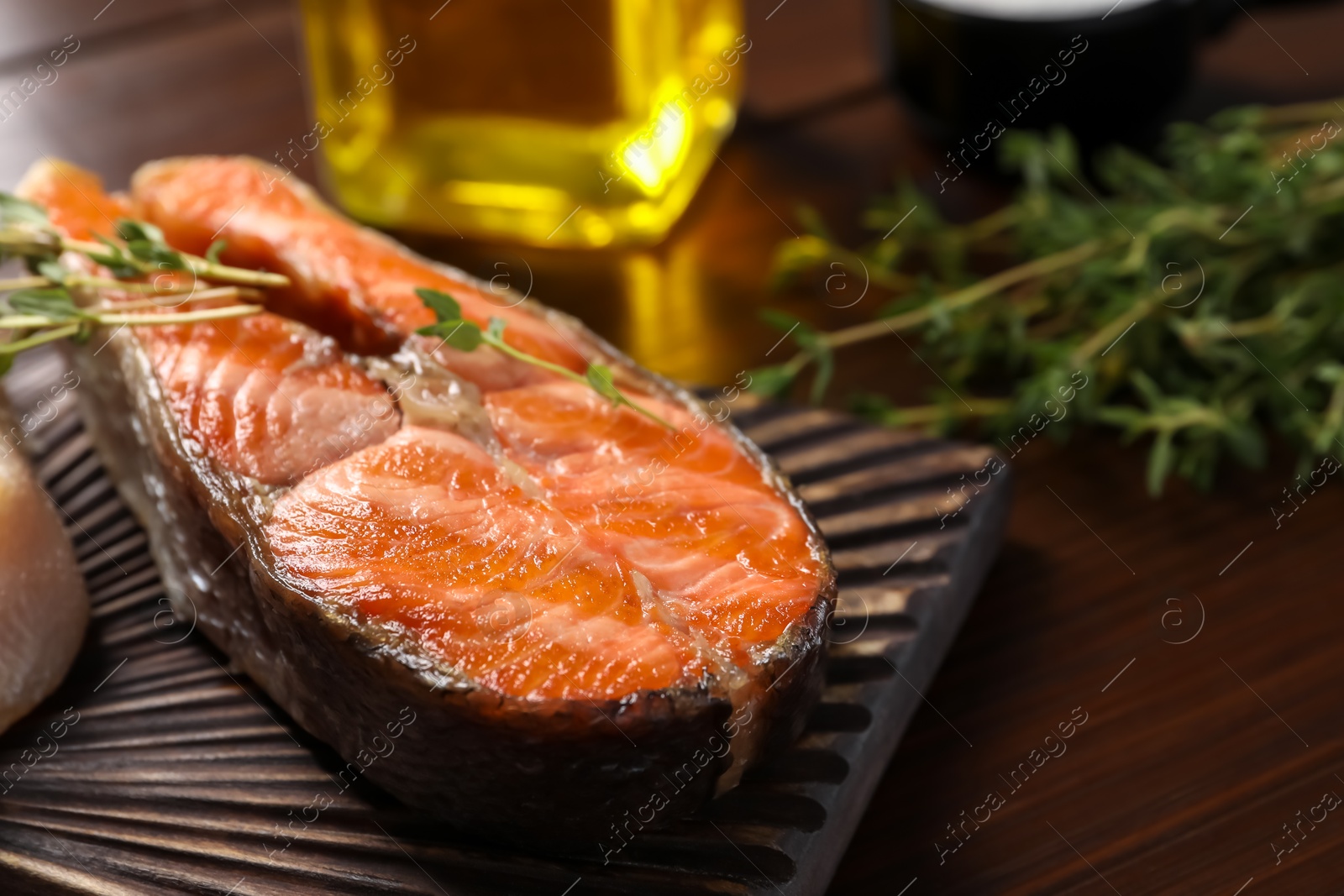 Photo of Tasty grilled salmon steak, and thyme on wooden table, closeup