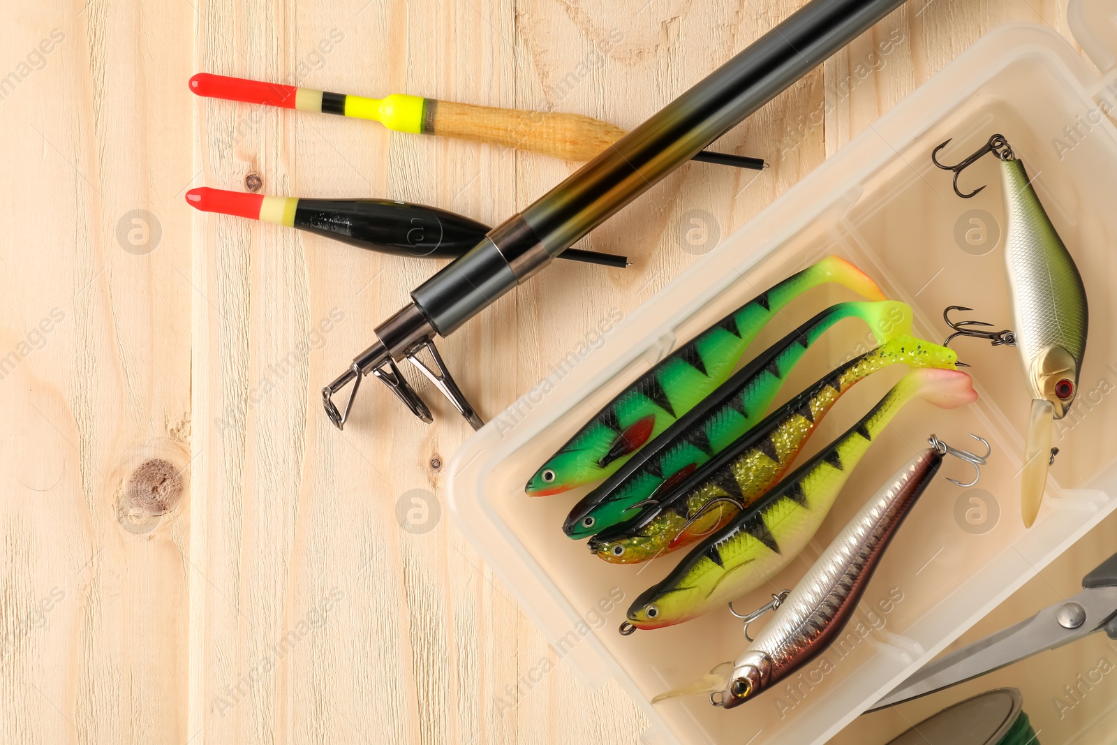 Photo of Fishing rod, baits, floats and scissors on wooden table, top view