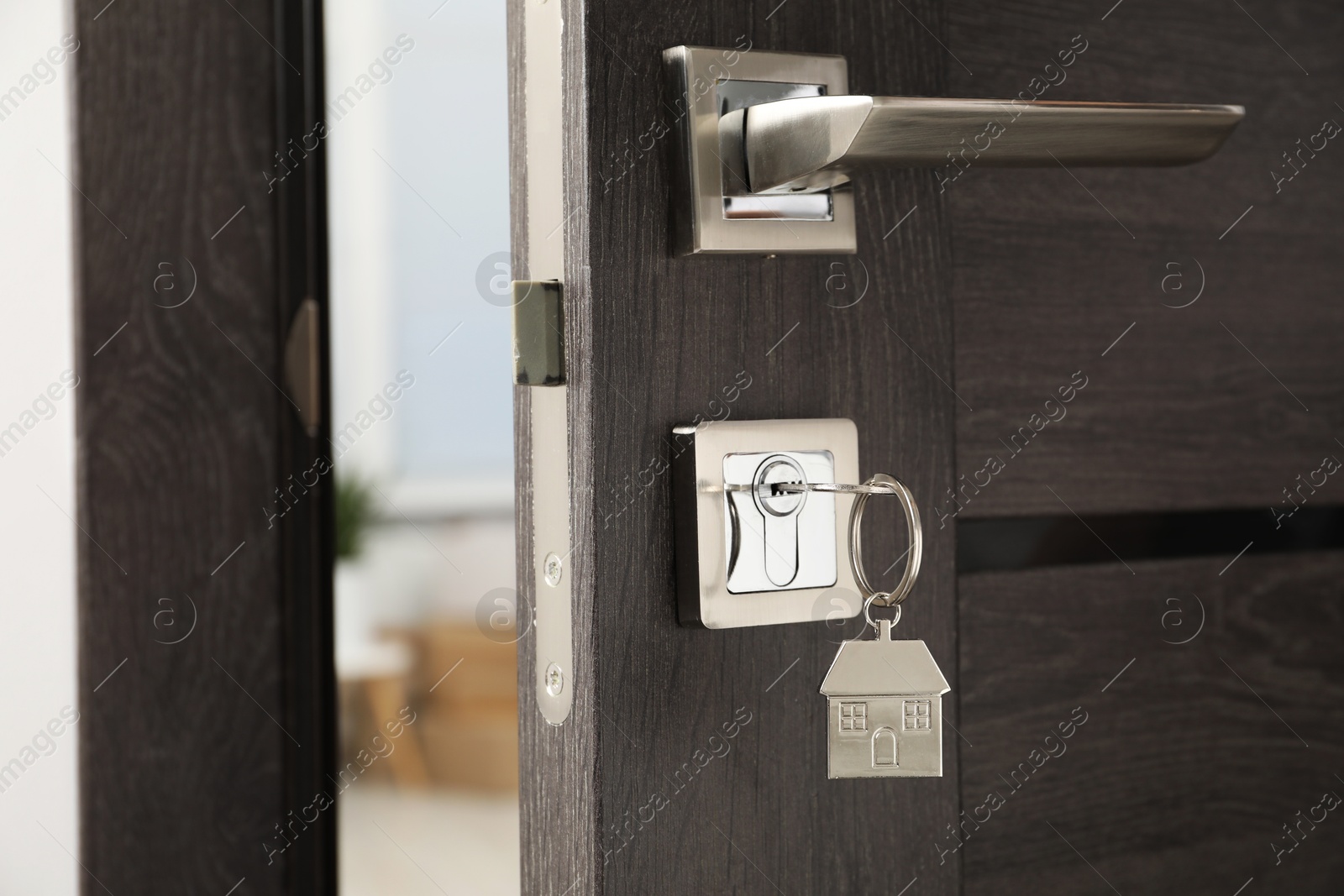 Photo of Open door with key and house shaped keychain, closeup