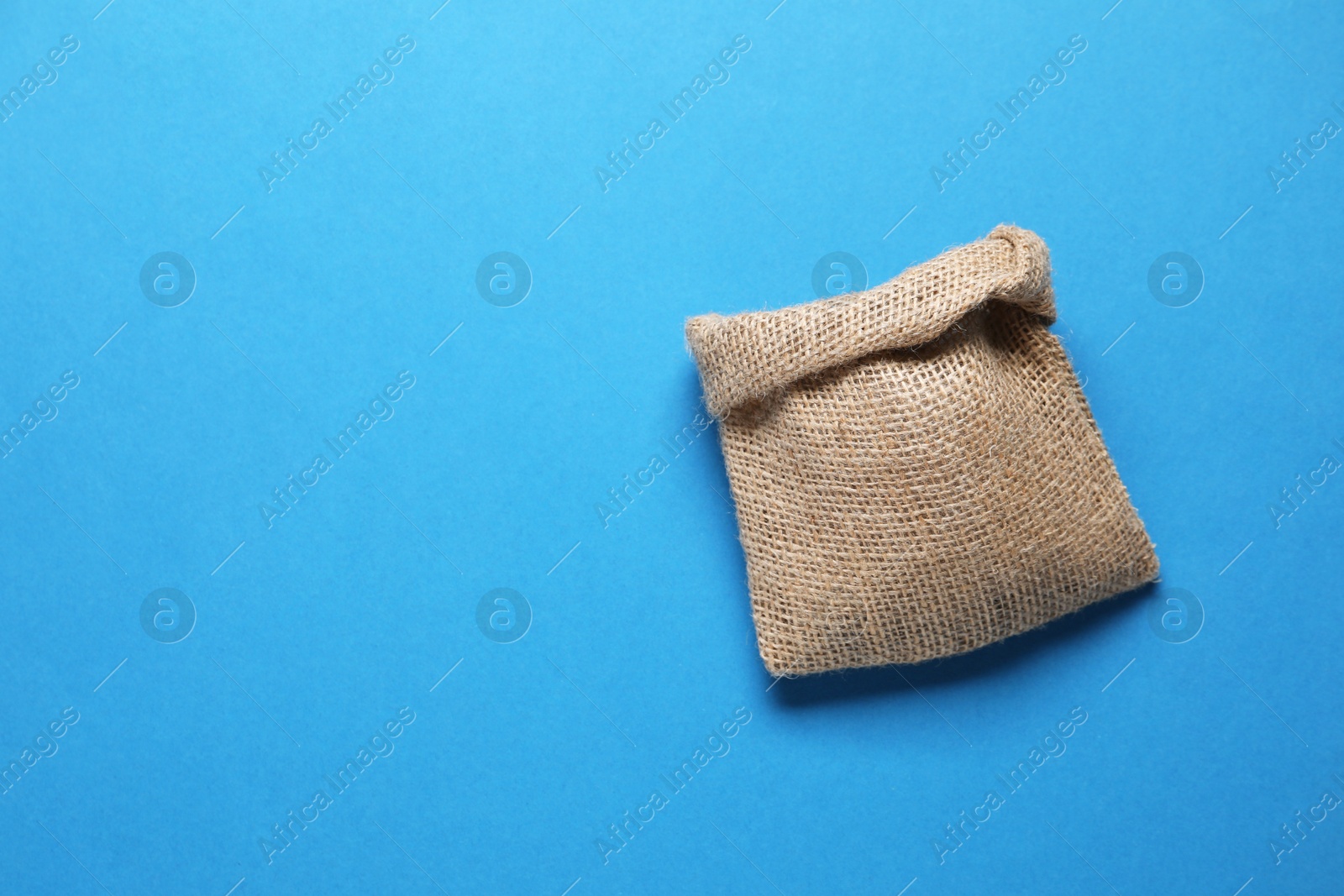 Photo of One burlap sack on light blue background, top view. Space for text