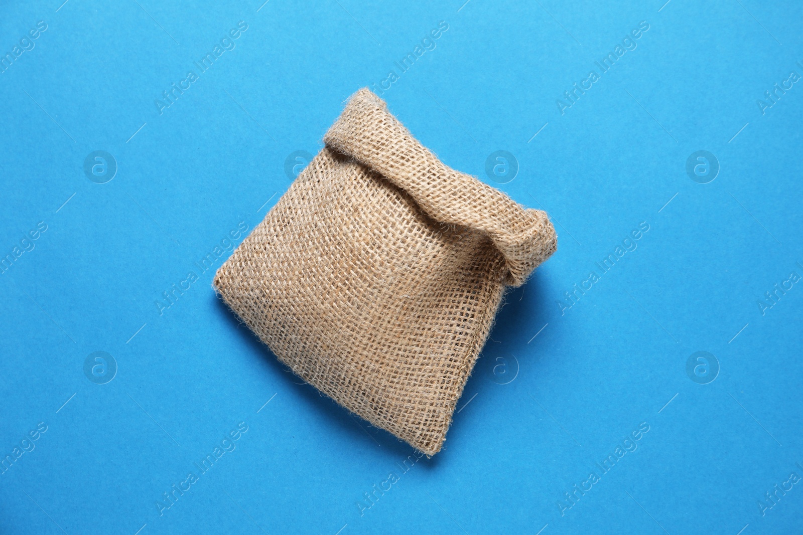 Photo of One burlap sack on light blue background, top view