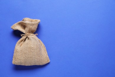 One burlap sack on blue background, top view. Space for text