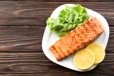 Photo of Delicious grilled salmon fillet served on wooden table, top view