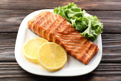 Photo of Delicious grilled salmon fillet served on wooden table, closeup