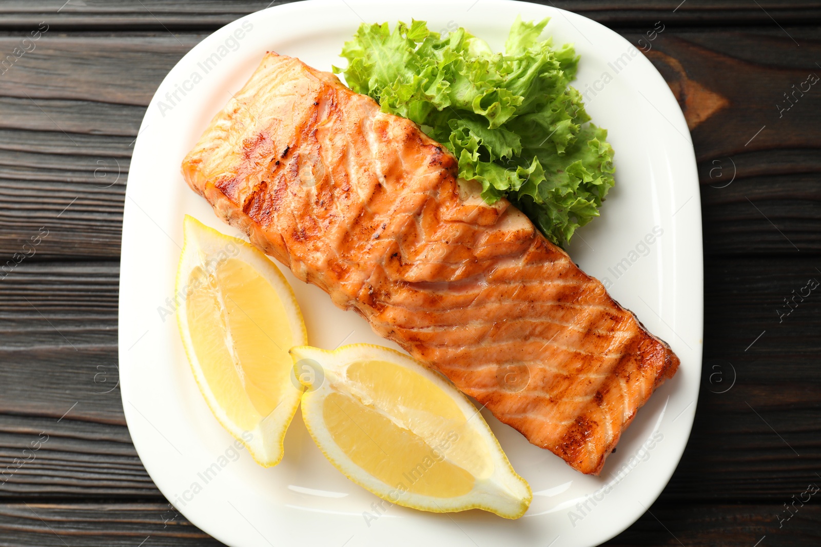 Photo of Delicious grilled salmon fillet served on wooden table, top view