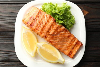 Photo of Delicious grilled salmon fillet served on wooden table, top view