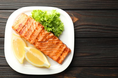 Photo of Delicious grilled salmon fillet served on wooden table, top view