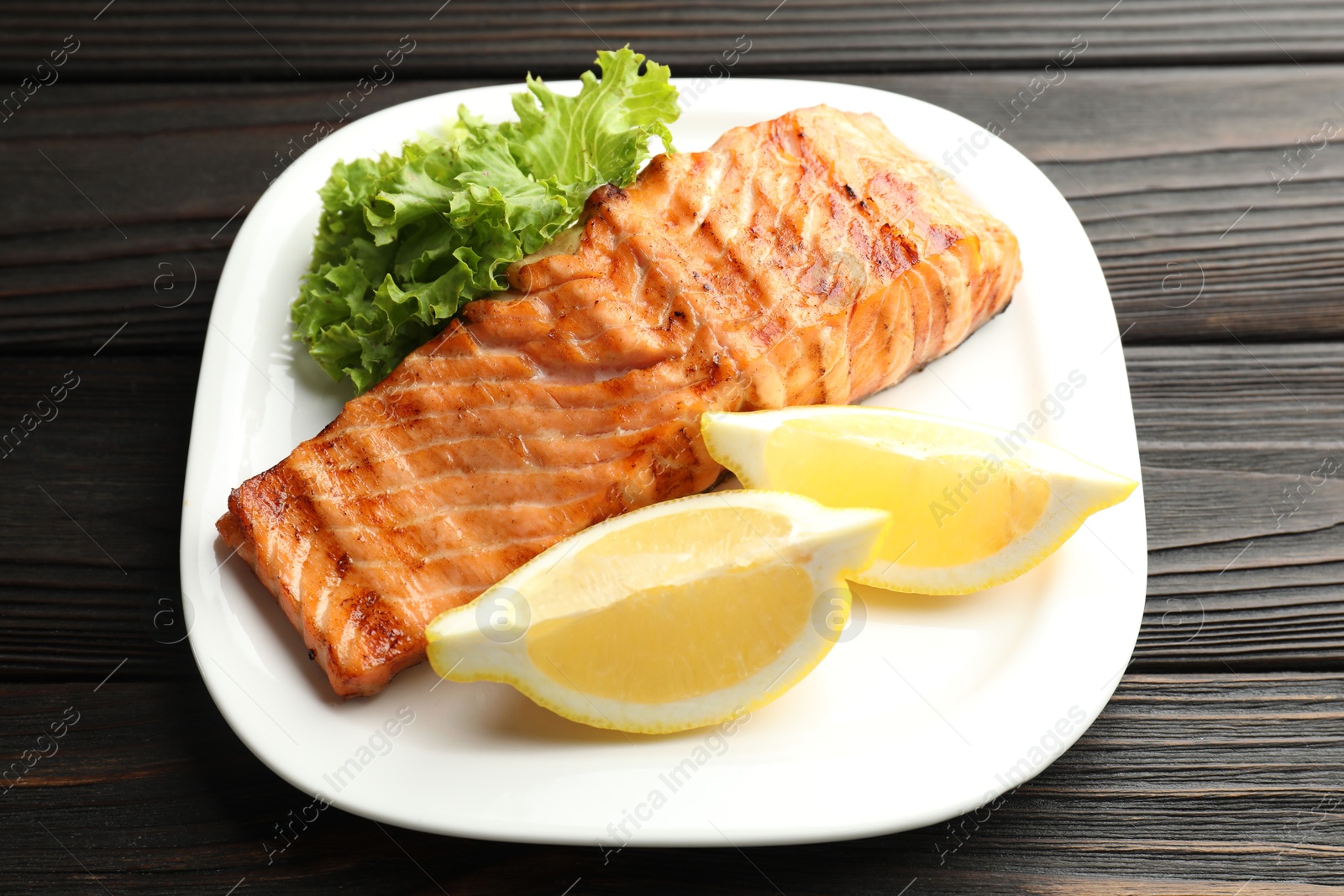 Photo of Delicious grilled salmon fillet served on wooden table, closeup