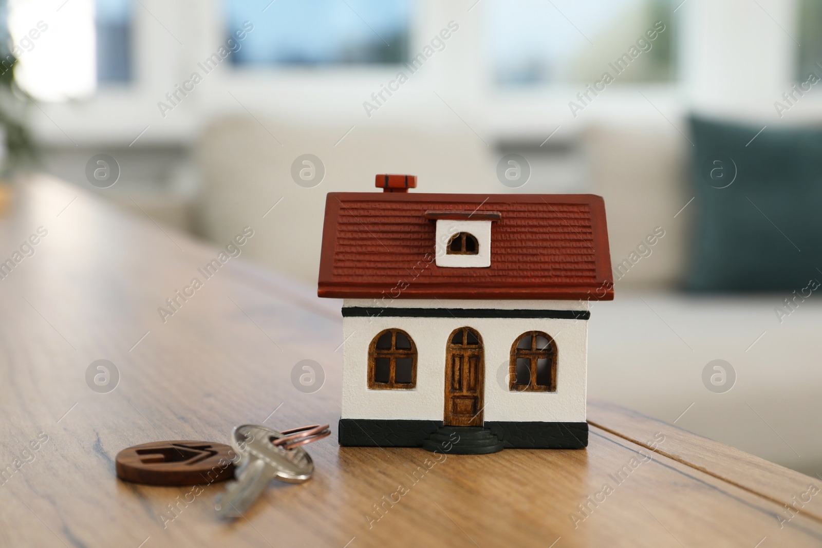 Photo of House model and key on wooden table indoors