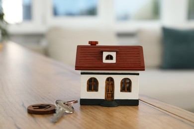 Photo of House model and key on wooden table indoors