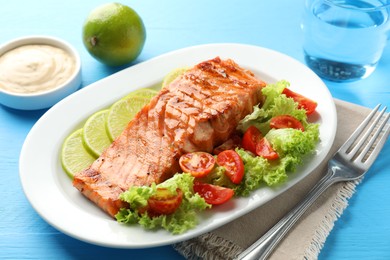 Photo of Delicious grilled salmon fillet served on light blue wooden table, closeup