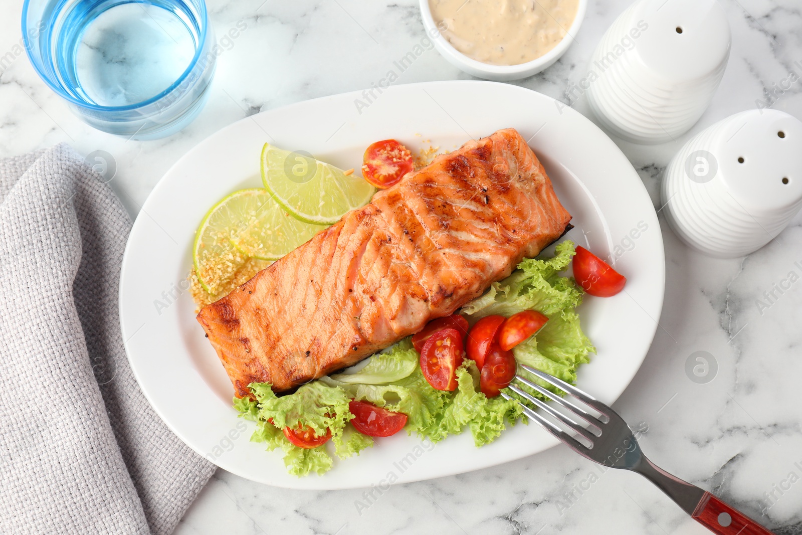 Photo of Delicious grilled salmon fillet served on white marble table, flat lay