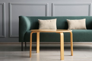 Photo of Stylish sofa with cushions and coffee table in room