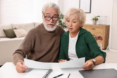 Photo of Pension savings. Senior couple planning budget at white table indoors