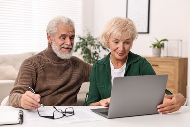 Pension savings. Senior couple planning budget at white table indoors