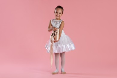 Little ballerina with pointe shoes on pink background