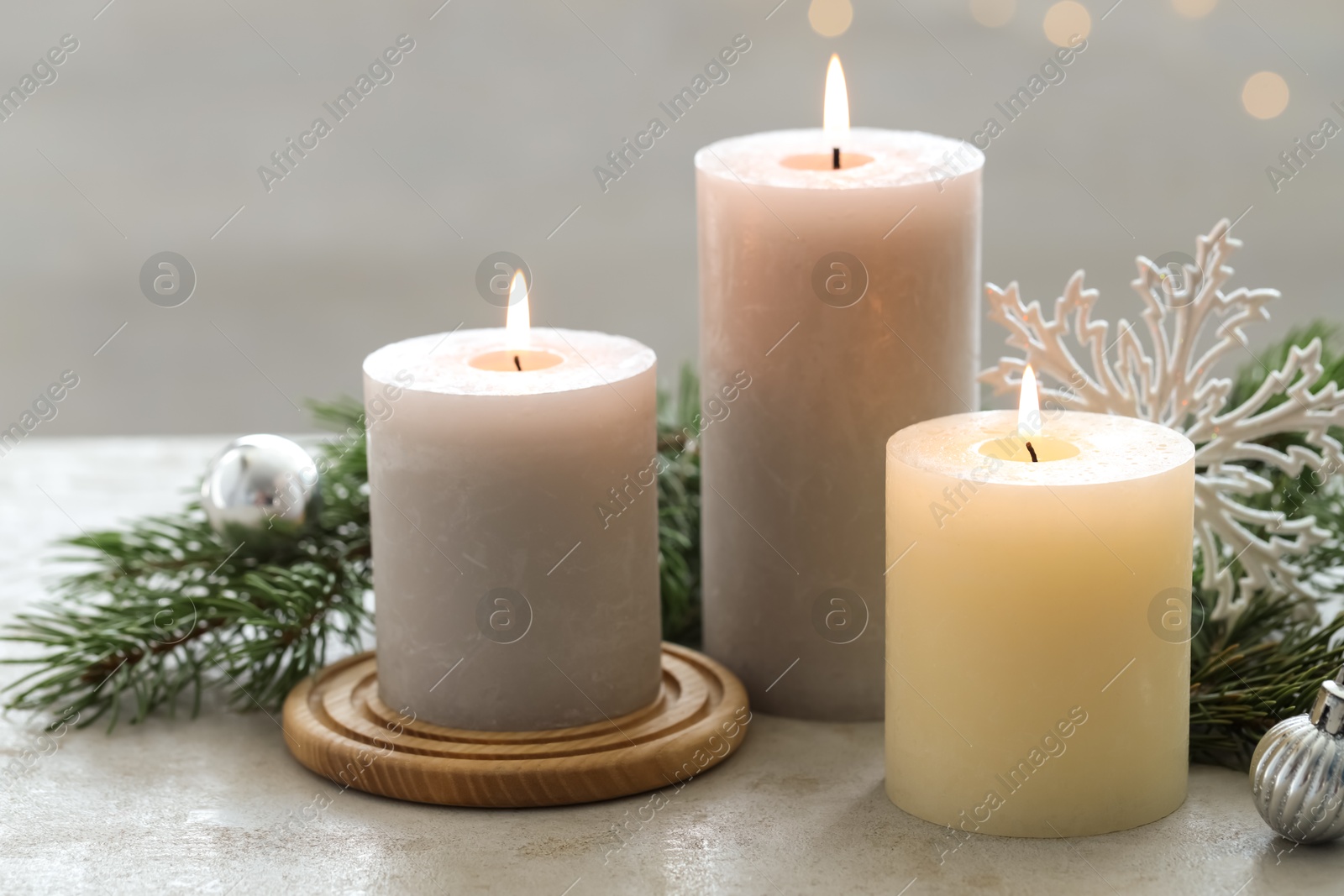 Photo of Burning candles, baubles and fir tree branches on white textured table, closeup