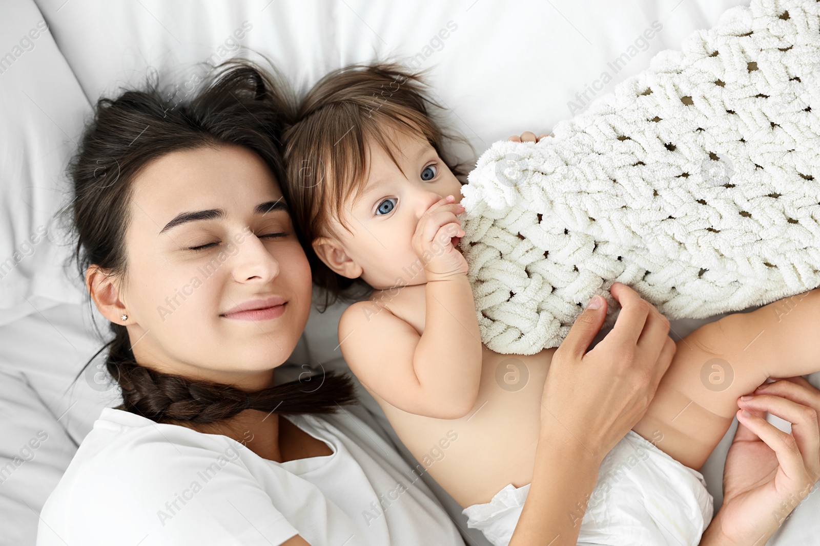 Photo of Beautiful young mother with her cute little baby on bed