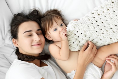 Photo of Beautiful young mother with her cute little baby on bed