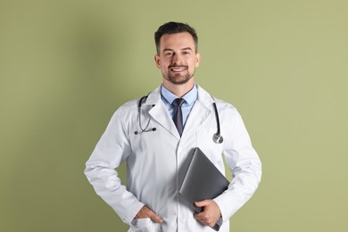 Photo of Smiling doctor with stethoscope and laptop on olive background