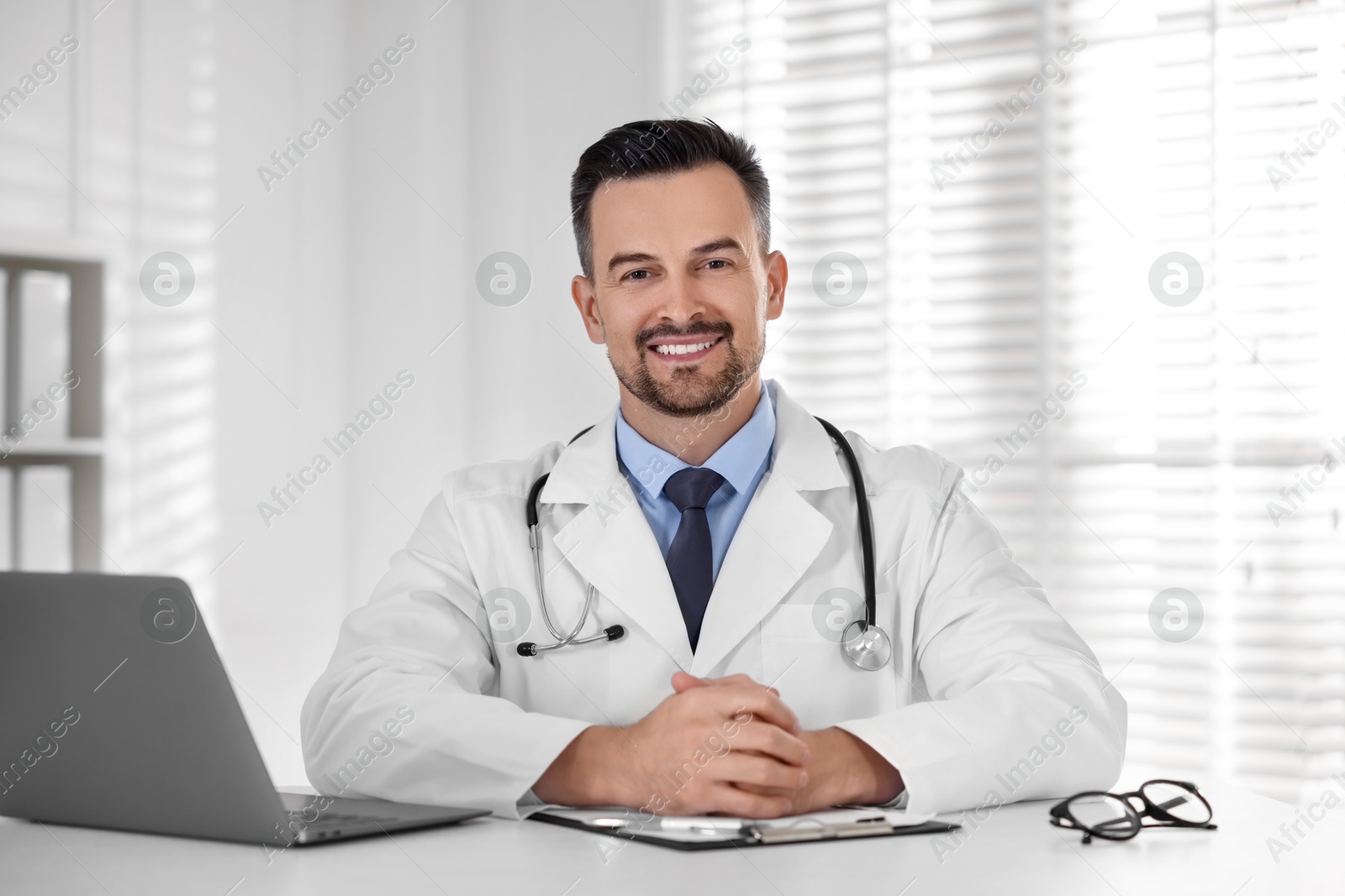 Photo of Smiling doctor working at table in clinic