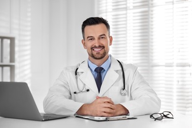 Photo of Smiling doctor working at table in clinic