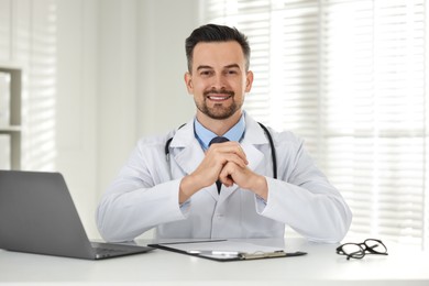 Photo of Smiling doctor working at table in clinic