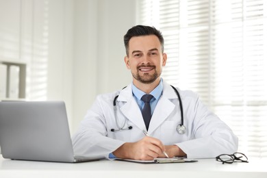 Photo of Smiling doctor working at table in clinic