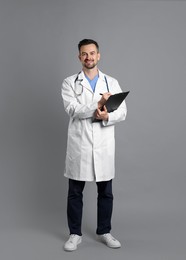 Smiling doctor with stethoscope and clipboard on grey background