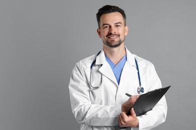 Smiling doctor with stethoscope and clipboard on grey background, space for text