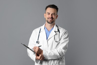 Photo of Smiling doctor with stethoscope and clipboard on grey background