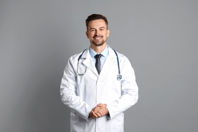 Smiling doctor with stethoscope on grey background