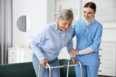 Nurse helping senior woman with walking frame indoors