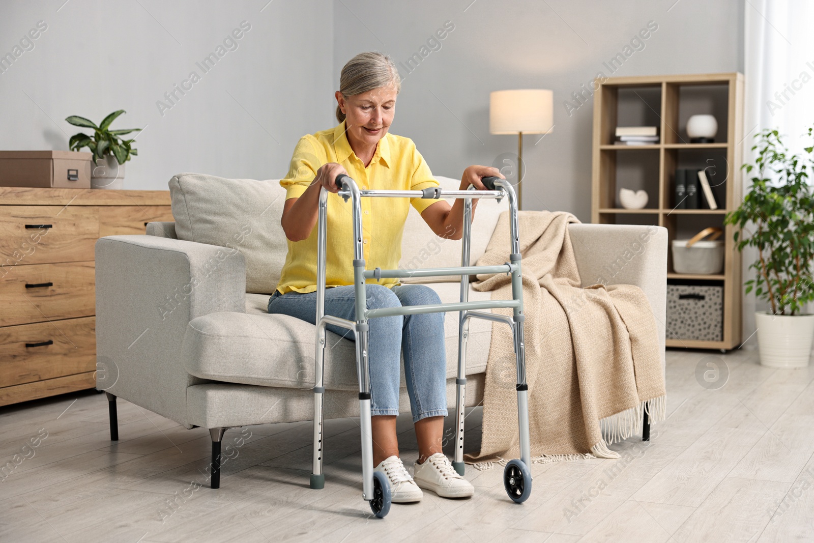 Photo of Senior woman with walking frame on sofa at home