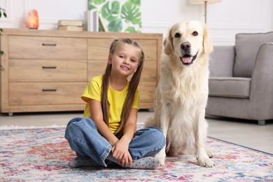 Girl with her cute Golden Retriever dog on rug at home