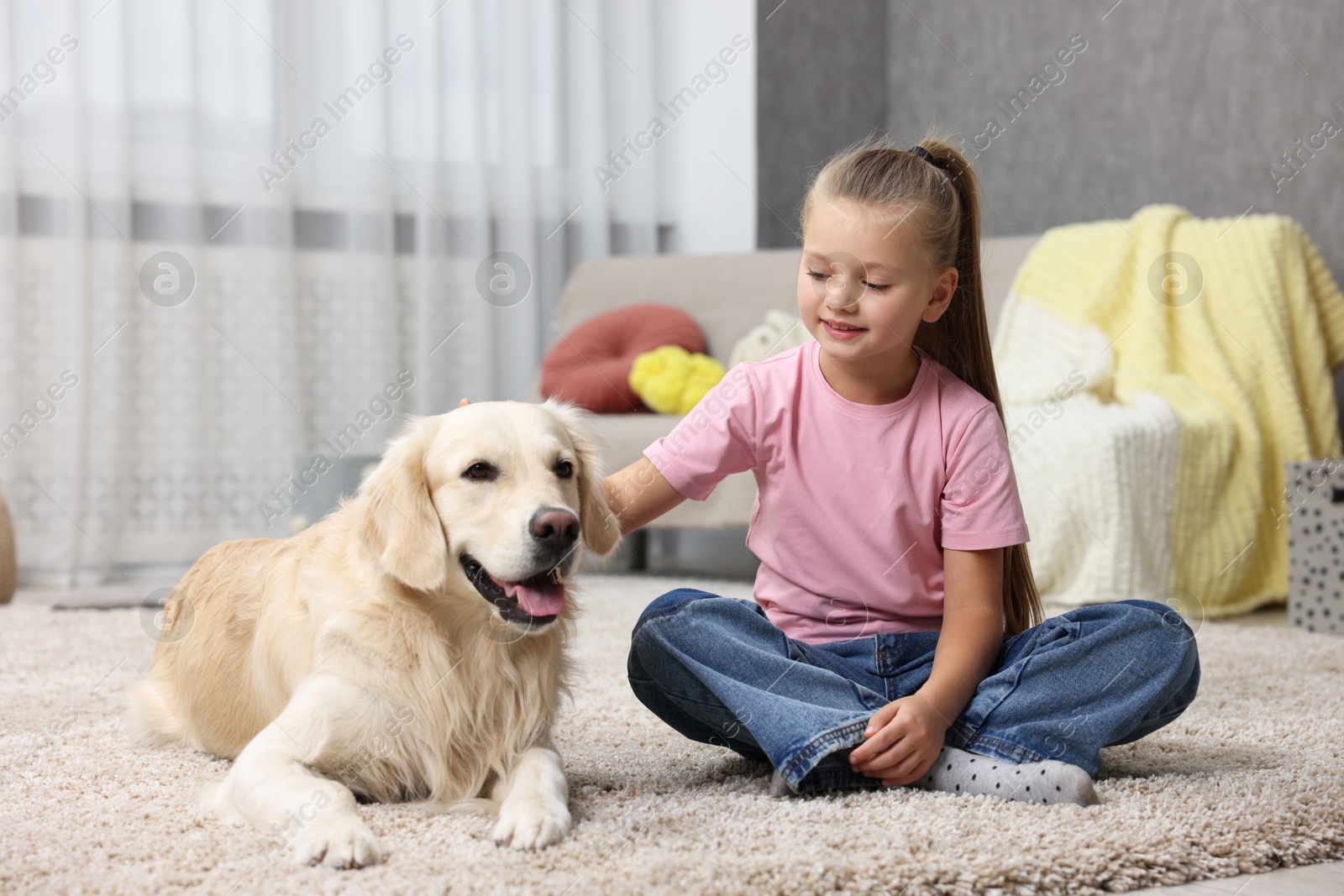 Photo of Girl with her cute Golden Retriever dog on rug at home