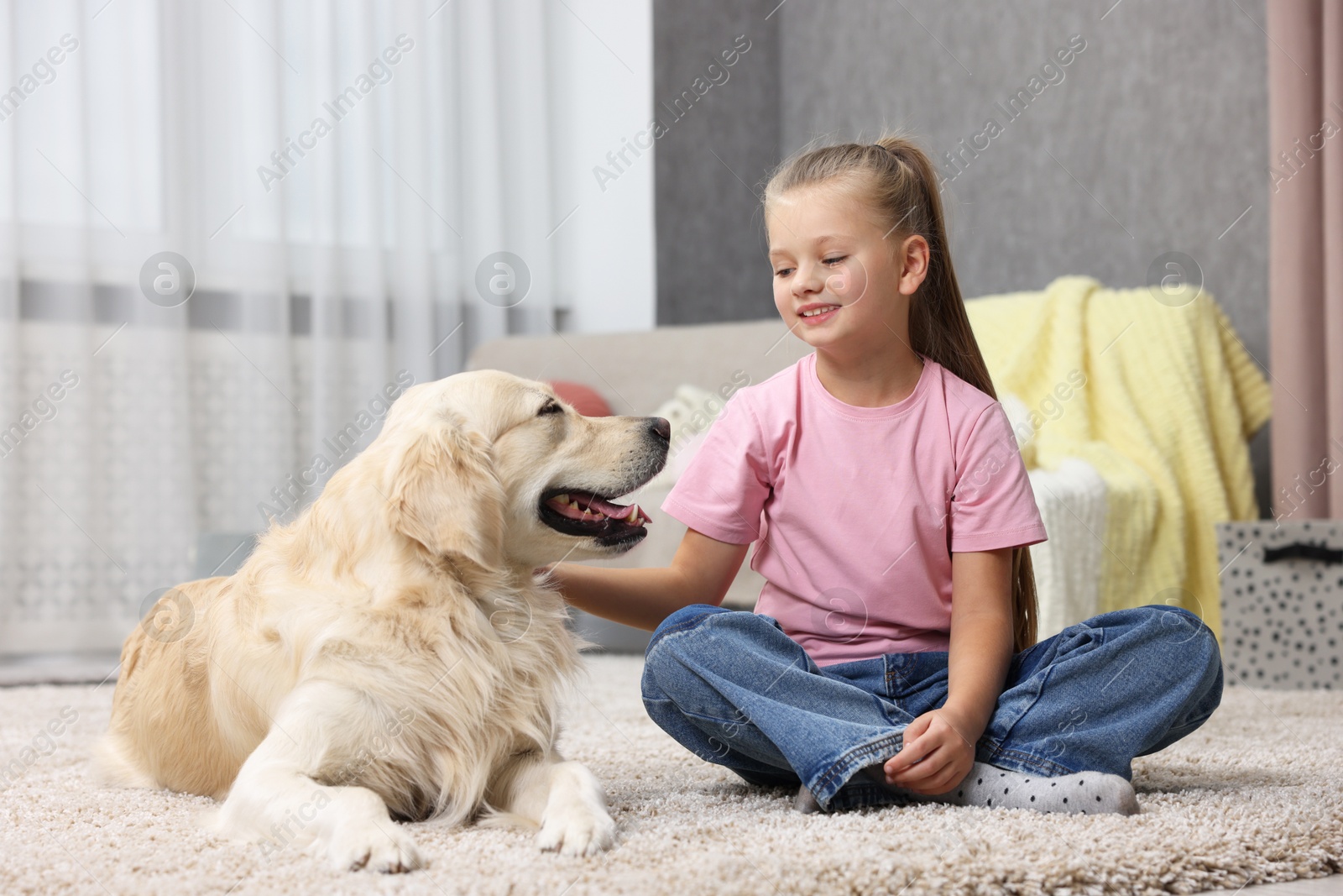 Photo of Girl with her cute Golden Retriever dog on rug at home