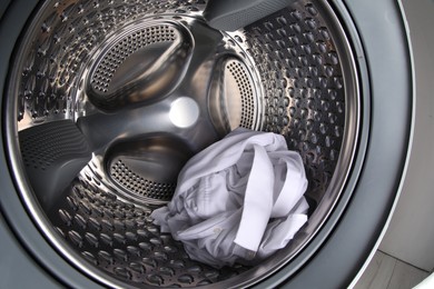 Photo of Washing machine with shirt as background, closeup