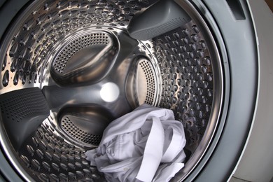 Photo of Washing machine with shirt as background, closeup