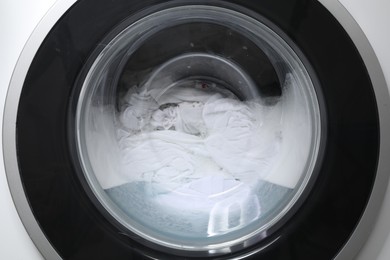 Washing machine with clothes and suds as background, closeup