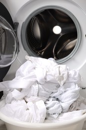 Basket with laundry near washing machine, closeup